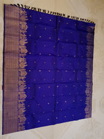 Load image into Gallery viewer, A royal blue silk saree with gold zari motifs and a wide beige border, laid flat against a light patterned background.
